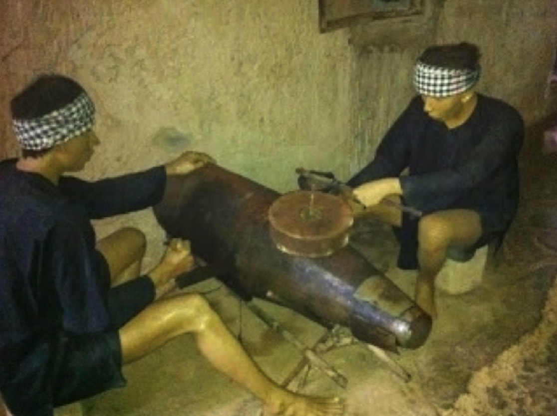 Modelos representando os guerrilheiros desmontando bombas do inimigo que não haviam estourado, para retirar material e fazer armas.